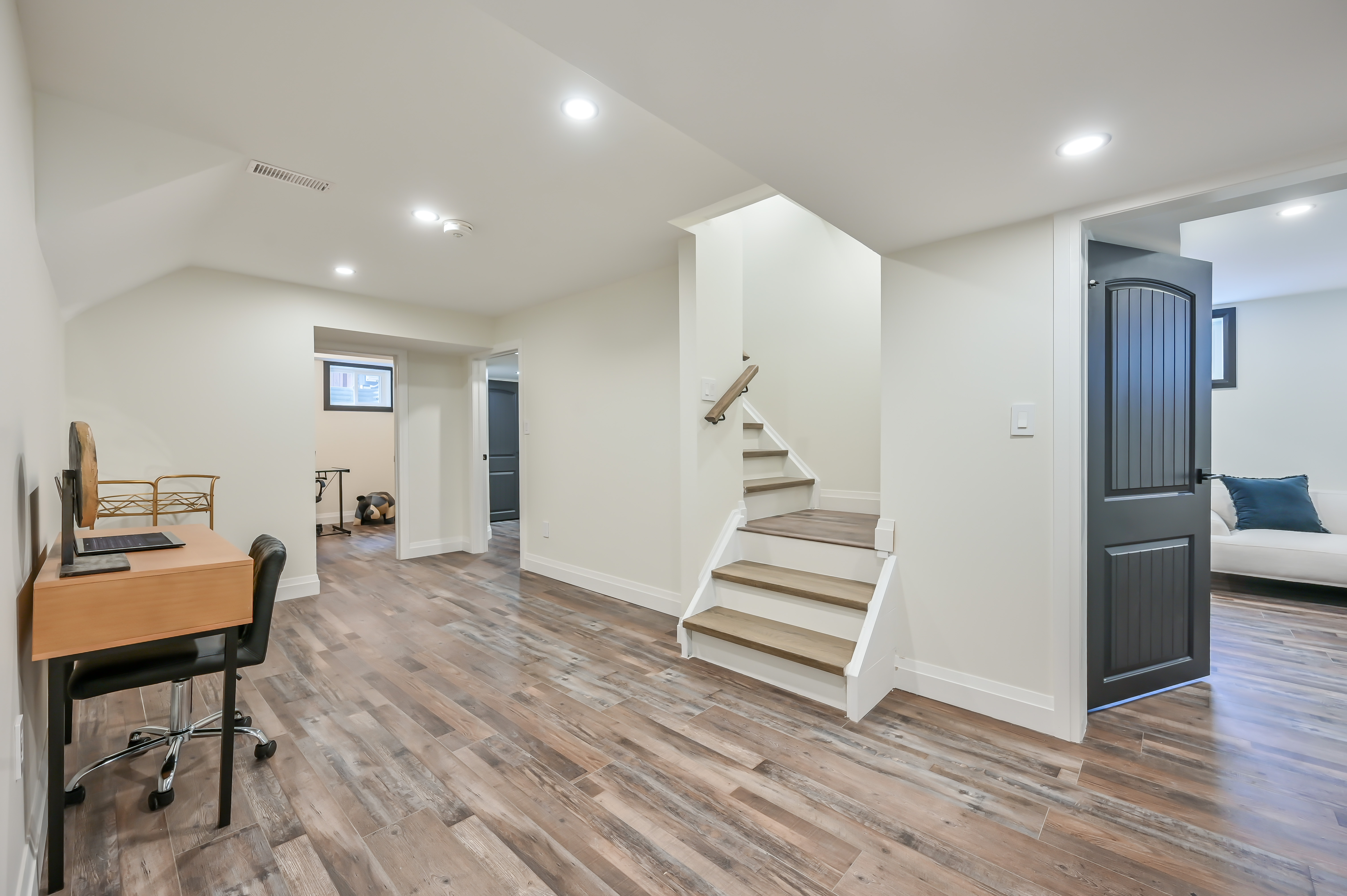 Professional wide-angle basement renovation with rich wood floors, clean lines, and excellent staging — premium portfolio shot — Kron, Hamilton | MTC Renovations